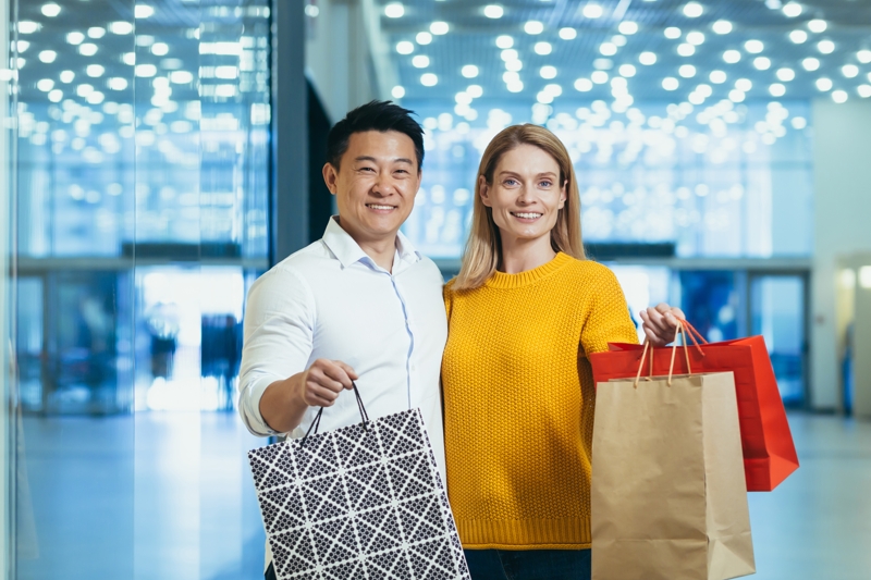 Young man and woman happy and holding bags in a mall.